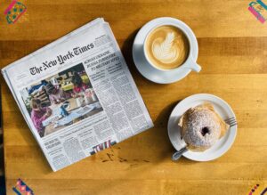 Photo of a Latte, Muffin, and Newspaper on a table