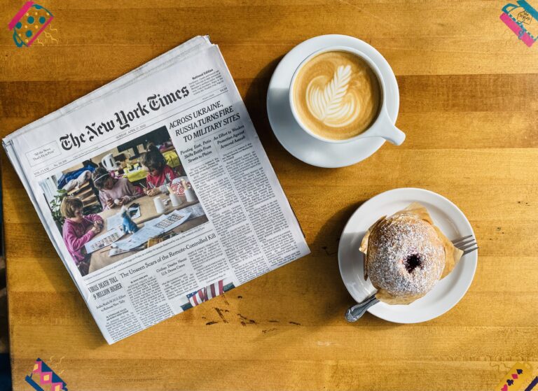 Photo of a Latte, Muffin, and Newspaper on a table