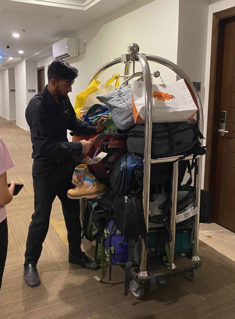 Giant pile of bags and luggage with a bell hop at a hotel