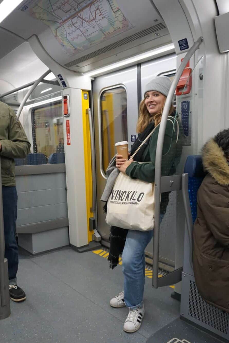 Mariah standing and riding the UBahn, the underground train in Munich Germany with tote bag and beanie on.